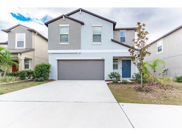 Two-story house with gray siding, gray garage door, and a blue front door at 16719 Delia St, Wimauma, FL 33598