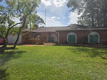 Single story home with orange exterior and landscaped lawn at 2280 Toniwood Ln, Palm Harbor, FL 34685