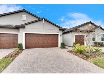 Two-car garage with paver driveway and well-manicured landscaping at 31428 Briars Ml, San Antonio, FL 33576