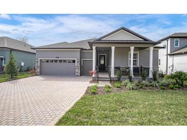 Gray two-story house with gray roof, paver driveway, and covered porch at 4661 Southern Valley Loop, Brooksville, FL 34601