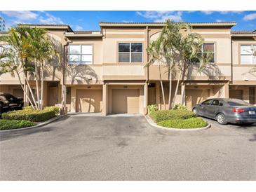 Tan townhouses with attached garages and lush landscaping at 809 Normandy Trace Rd, Tampa, FL 33602
