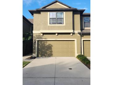 Two-story townhome with tan exterior, attached garage and concrete driveway at 5153 Bay Isle Cir, Clearwater, FL 33760