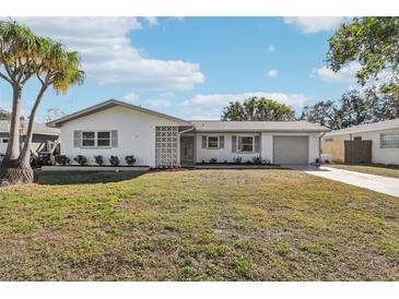 White house with gray roof, landscaping, and driveway at 10904 90Th Ter, Seminole, FL 33772