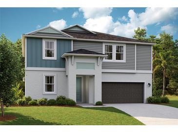 Two-story home with gray and teal siding, dark garage door, and landscaped lawn at 14445 Meadow Bird Ave, Riverview, FL 33579