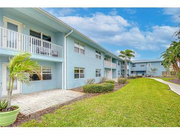 Light blue building with balconies, lush landscaping, and a paved walkway at 300 Venetian Dr # 7, Clearwater, FL 33755