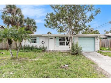 Ranch-style home with light brick exterior, teal garage door, and mature landscaping at 6702 Sandra Dr, Port Richey, FL 34668