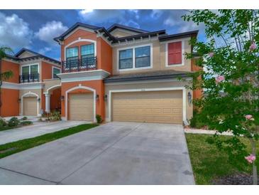 Two-story townhome with tan and orange exterior, two-car garage, and landscaped lawn at 9135 Fox Sparrow Rd, Tampa, FL 33626