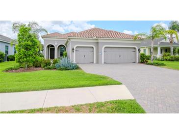 Two-story house with three-car garage, manicured lawn, and tile driveway at 1069 River Wind Cir, Bradenton, FL 34212