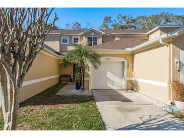 Tan two-story townhome with a white garage door and walkway at 8907 Casablanca Way, Tampa, FL 33626
