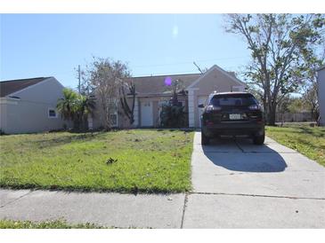 Tan one-story house with a driveway and small yard at 1621 Crossridge Dr, Brandon, FL 33510