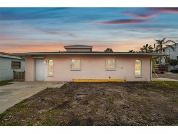 Pink single story home with gray roof, landscaping, and a small yard at 306 180Th E Ave, Redington Shores, FL 33708