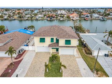 Aerial view of waterfront home with two-car garage and landscaped yard at 11325 5Th E St, Treasure Island, FL 33706