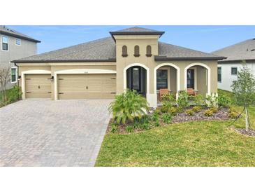 Single-story house with tan exterior, landscaping, and two-car garage at 13028 Homestead Ln, Parrish, FL 34219