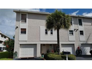 Two-story condo building with attached garages, landscaping, and palm trees at 255 Capri N Cir # 17, Treasure Island, FL 33706