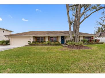 Single story home with attached garage, manicured lawn, and large shade tree at 3756 E Lake Dr, Land O Lakes, FL 34639