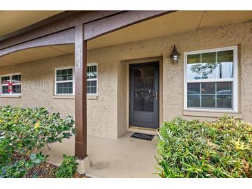Inviting condo entryway with covered porch, lush landscaping, and a black front door at 601 N Hercules Ave # 503, Clearwater, FL 33765