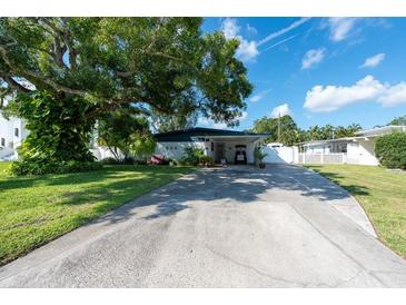 Ranch-style home with carport, mature landscaping, and spacious driveway at 604 Danube Ave, Tampa, FL 33606