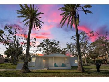 Charming bungalow with a white exterior, covered porch, and two palm trees at 402 Pineapple St, Tarpon Springs, FL 34689