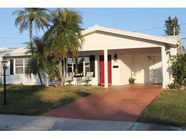 White single-story home with red door, palm trees, and a terracotta driveway at 9705 45Th N Way, Pinellas Park, FL 33782