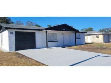 Newly renovated home featuring a modern exterior, fresh paint, and a new driveway at 10205 Cherry Creek Ln, Port Richey, FL 34668