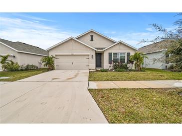 Tan two-story house with a two-car garage and landscaped lawn at 17019 Avon Dive Ln, Wimauma, FL 33598