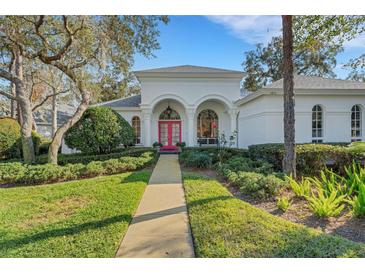 White house with pink door, landscaped yard, and walkway at 2850 Deer Run, Tarpon Springs, FL 34688