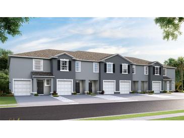 Two-story townhouses with gray siding, white garage doors, and landscaping at 32591 Turtle Grace Loop, Wesley Chapel, FL 33545