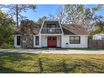 A charming A-frame house with a red door and stone chimney at 705 Whiteway Dr, Brooksville, FL 34601