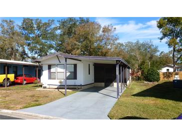 Mobile home with carport and well-maintained lawn at 34421 Countryside Dr, Wesley Chapel, FL 33543