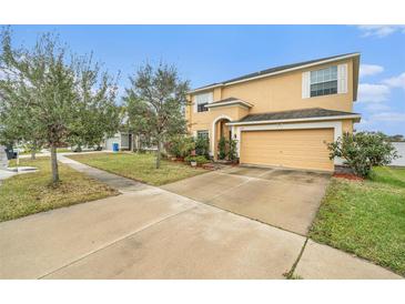 Two-story house with a tan exterior, two-car garage, and landscaping at 534 19Th Nw St, Ruskin, FL 33570