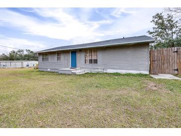 Ranch style home with gray siding, blue door, and grassy yard at 14430 10Th. St, Dade City, FL 33523