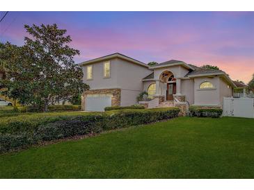 Two-story house with stone accents, landscaped lawn, and a two-car garage at 720 Sunset Dr, Tarpon Springs, FL 34689