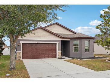 One-story house with brown garage door and gray siding at 15541 Sword Lily Pl, Brooksville, FL 34604