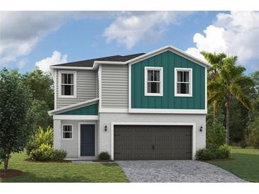 Two-story house with gray and teal siding, a two-car garage, and a landscaped lawn at 37290 Sagemoor Dr, Zephyrhills, FL 33541