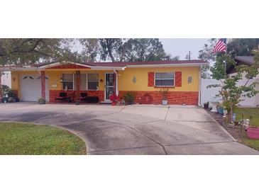 Ranch-style home with yellow and red exterior, mature landscaping, and a spacious driveway at 4360 82Nd N Ave, Pinellas Park, FL 33781