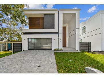 Modern two-story home with a sleek design and a glass garage door at 3010 W Trilby Ave, Tampa, FL 33611