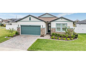 Two-story house with a teal garage door, stone accents, and a manicured lawn at 34432 Wynthorne Pl, Wesley Chapel, FL 33545