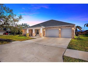 Brick house with a three-car garage and manicured lawn at 2402 Cumberland Cliff Dr, Ruskin, FL 33570