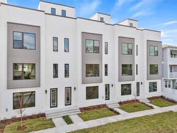 Modern three-story townhouses with gray and white exterior, landscaping, and sidewalks at 2506 W Cleveland St # 18, Tampa, FL 33609