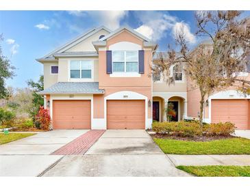 Two-story townhome with peach-colored exterior, two-car garage, and landscaped front yard at 26519 Castleview Way, Wesley Chapel, FL 33544