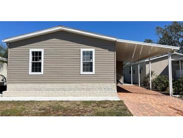Well-maintained home exterior with vinyl siding, brick foundation, and a covered carport at 3729 Winward Lakes Dr, Tampa, FL 33611