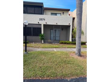 Exterior view of condo with address number 2571, landscaping, and a walkway at 2571 Cyprus Dr # 1-105, Palm Harbor, FL 34684