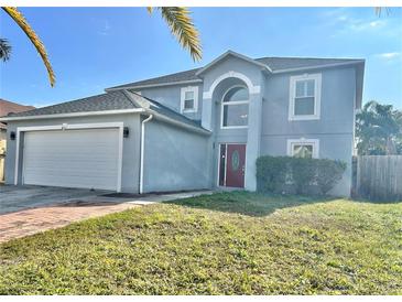 Two-story house with a gray exterior, red door, and a white garage door at 24932 Ravello St, Land O Lakes, FL 34639