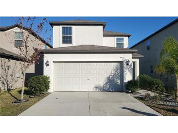 Two-story house with a white exterior, two-car garage, and landscaping at 4410 Summer Savory St, Tampa, FL 33619
