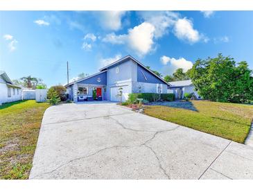Cute Florida home with gray exterior, red door, and nicely landscaped lawn at 3113 Chamblee Ln, Clearwater, FL 33759