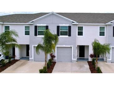 Two-story townhome with gray siding, two-car garage, and landscaping at 32535 Turtle Grace Loop, Wesley Chapel, FL 33545