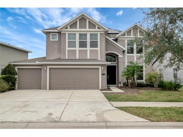 Two-story house with three-car garage, landscaping, and neutral color palette at 19354 Yellow Clover Dr, Tampa, FL 33647