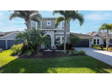 Two-story house with gray siding, dark garage door, and lush landscaping at 6609 Current Dr, Apollo Beach, FL 33572