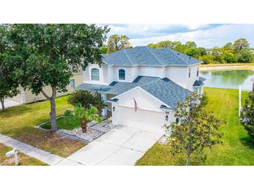 Two-story house with a lake view, and a well-manicured lawn at 3533 Juneberry Drive, Wesley Chapel, FL 33543
