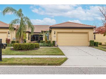 Front view of a tan, single-story house with a two-car garage and landscaping at 417 Brandywine Falls Ct, Apollo Beach, FL 33572